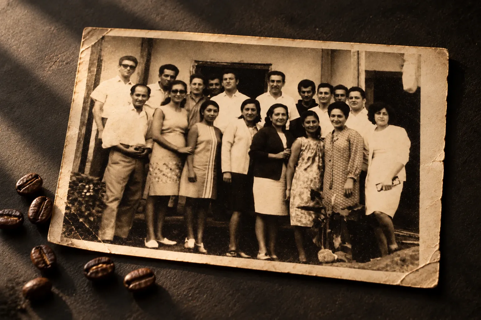 Fotografía antigua en sepia de un grupo de personas, junto a granos de café sobre una superficie oscura.
